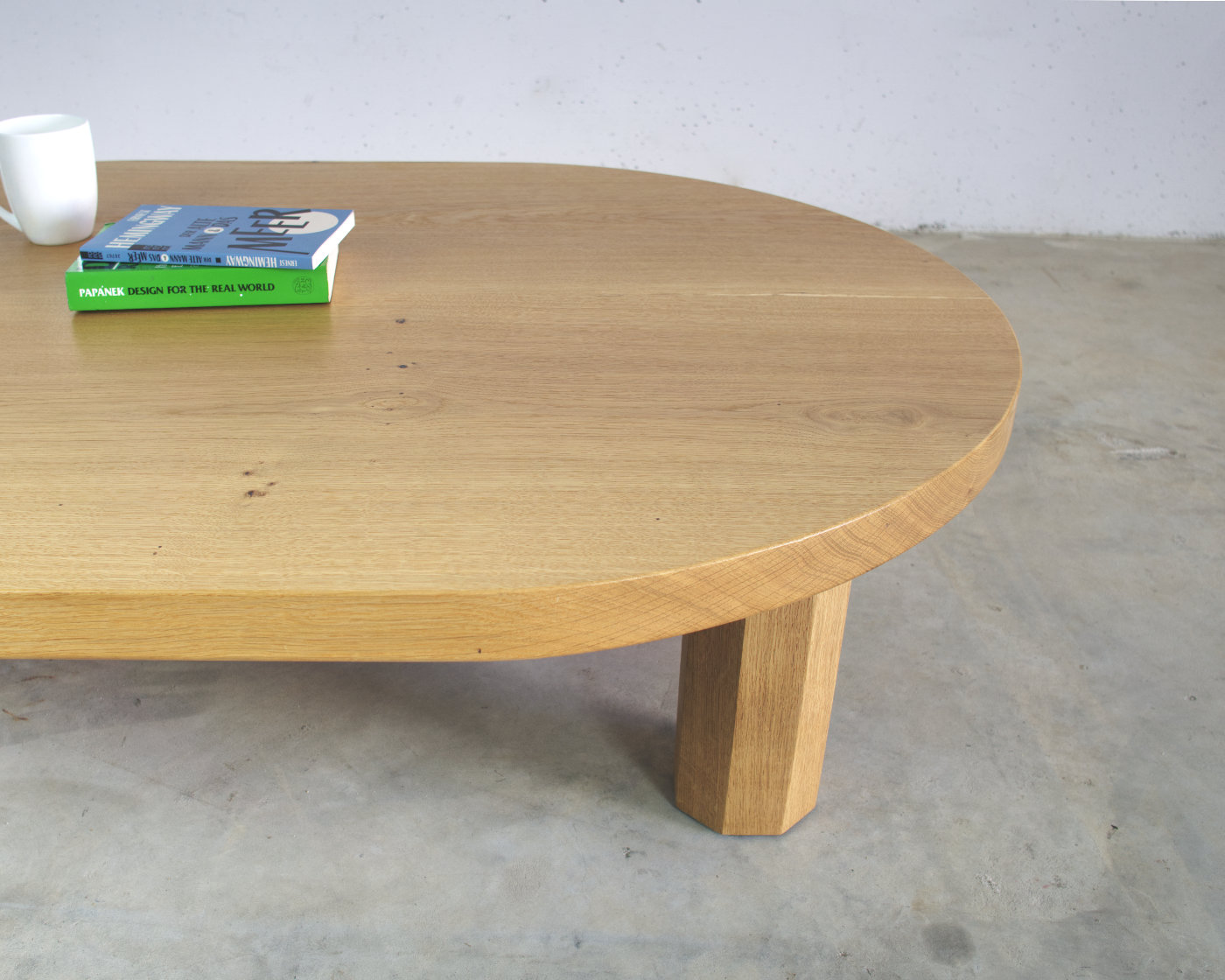 seitenansicht couchtisch massivholz eiche oval mit achteckigen beinen darauf buch